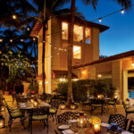 Cozy outdoor dining area with warm lighting and tropical ambiance at dusk.