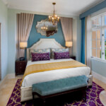 Elegant bedroom with teal accent wall and luxurious bedding.