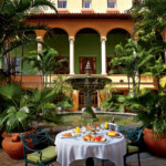 Elegant outdoor dining setup in a lush courtyard with tropical plants.