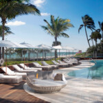 Luxurious poolside lounge area with palm trees and ocean views.