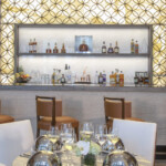 Elegant bar with stylish seating and illuminated shelves displaying liquor bottles.