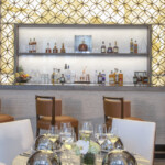 Elegant bar with stylish seating and illuminated shelves displaying liquor bottles.