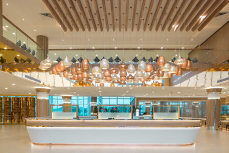 Modern cafeteria interior with hanging light fixtures and wooden ceiling design.