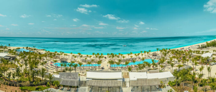 default Aerial view of a sunny beach with umbrellas and calm ocean waves.