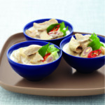 Three blue bowls of creamy chicken curry with chili and herbs.