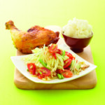 Grilled chicken leg with a fresh vegetable salad and a bowl of rice.