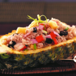 Pineapple boat filled with colorful rice and vegetables.