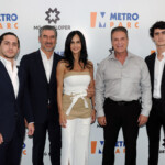 Five well-dressed people pose at a Metro Metro event backdrop.
