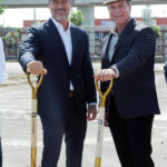Two men in suits holding golden shovels at a groundbreaking event.