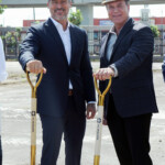 Two men in suits holding golden shovels at a groundbreaking event.