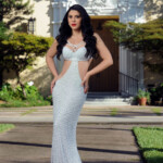 Elegant woman in a white lace gown posing outdoors.
