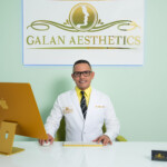 Professional aesthetician in white coat at his reception desk.