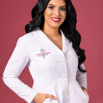 Confident woman in a white medical coat against a red background.
