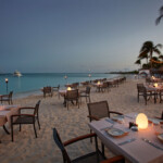 Beachfront dining setup with tables and chairs at dusk.