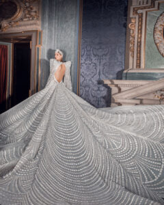 Elegant bride in a detailed, flowing wedding gown with a long train.