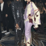 Two fashion-forward individuals posing at an event, showcasing bold and unique outfits.