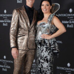 A stylish couple poses on the red carpet at a formal event.