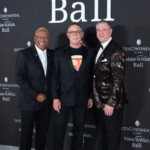 Three men posing at a formal event with a black backdrop.