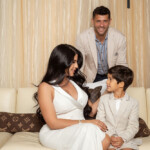 A happy family dressed elegantly, smiling together on a sofa.