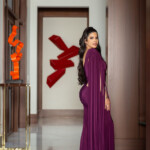 Woman in elegant purple dress posing indoors.