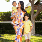 A woman in a floral dress with two children outdoors.