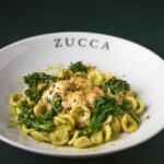 Creamy pasta garnished with green vegetables in a white Zucca bowl.