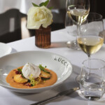 Elegant dining setup with creamy soup and white wine.