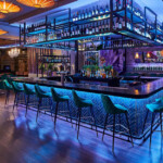 Modern bar with illuminated counter and stylish seating at night.