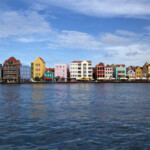 Colorful houses lined up along a waterfront under a blue sky.