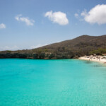 Turquoise water and sandy beach under a partly cloudy sky.