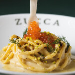 Creamy pasta topped with salmon roe and fresh dill served on a white plate.