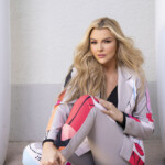 Confident woman in stylish activewear sitting against a wall.