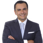 Delio Photo Studio - Business and Modeling Head Shot Photography in Miami Confident businessman in a suit smiling with arms crossed.