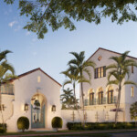 Elegant Mediterranean-style building surrounded by palm trees at dusk.