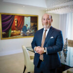 A well-dressed man standing confidently in a stylish dining room.