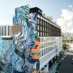 A tall building with vibrant blue and orange wave mural on its side.