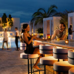 People enjoy drinks at a rooftop bar during twilight.