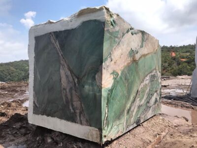 Large block of green and beige marble stone outdoors.