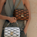 Two elegant designer handbags held by a stylish woman.