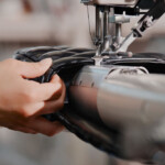 Close-up of hands sewing fabric on an industrial sewing machine.