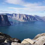 Stunning fjord with steep cliffs and calm blue water under a clear sky.