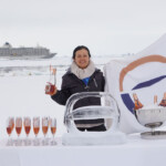 Person celebrating with a glass of champagne in a snowy setting.