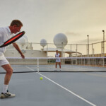 Two men playing pickleball on an outdoor court at sunset.