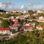 Scenic view of a hillside town with red-roofed buildings under a partly cloudy sky.