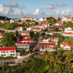 Scenic view of a hillside town with red-roofed buildings under a partly cloudy sky.