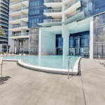 Modern outdoor pool with glass building backdrop on a sunny day.