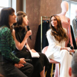 Laure Hériard Dubreuil, Lilah Ramzi, Victoria Beckham Three women engaged in a lively discussion during a fashion event.