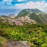 Scenic mountain town surrounded by lush green vegetation under a partly cloudy sky.