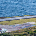 Helipad near the ocean with a small building and grassy surroundings.