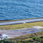 Helipad near the ocean with a small building and grassy surroundings.
